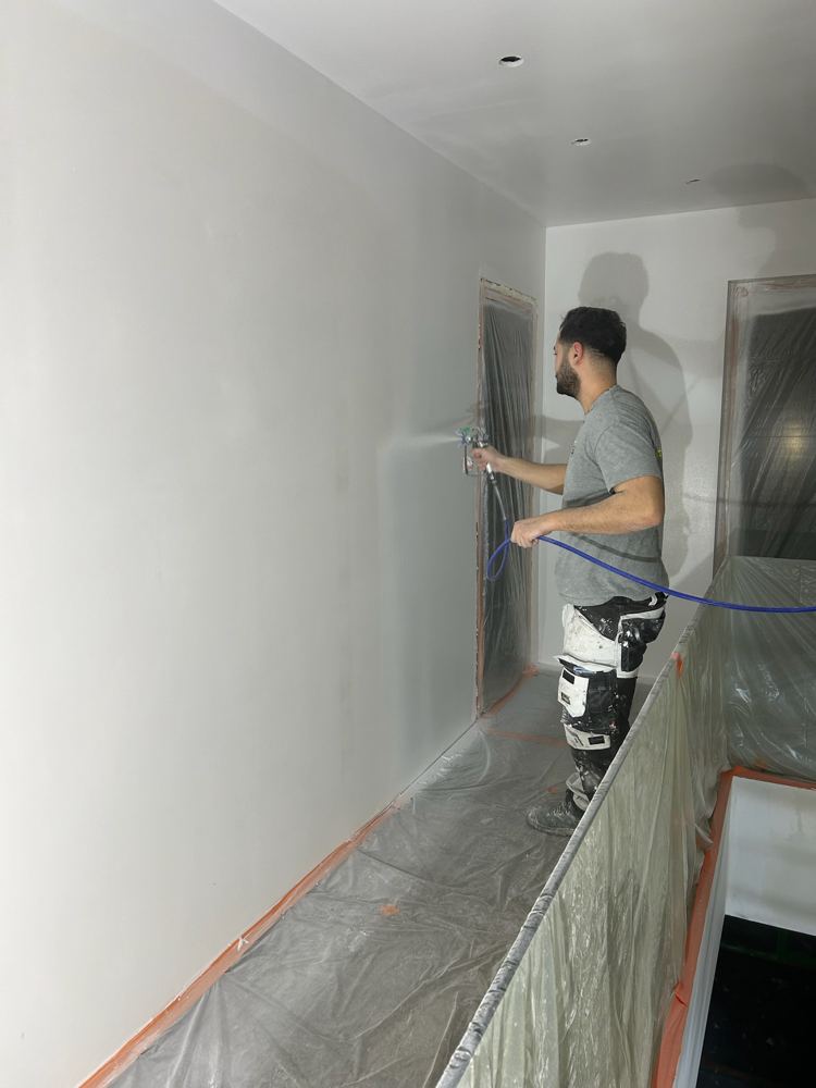 Peintre IKIS Rénov projetant la peinture sur un mur intérieur